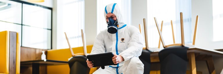A man in a protective suit with a mask holding an ipad A man in a protective suit with a mask holding an ipad