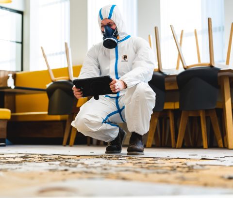 A man in a protective suit with a mask holding an ipad A man in a protective suit with a mask holding an ipad