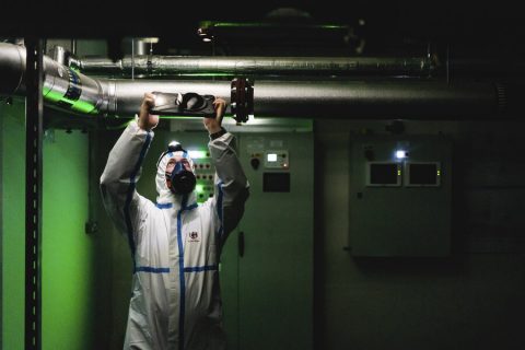 A man wearing a protective suit in the dark taking a photo of a value on an iPad A man wearing a protective suit in the dark taking a photo of a value on an iPad