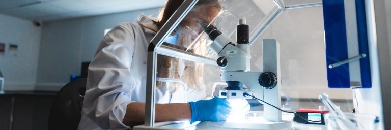 A woman looking into a telescope in a laboratory A woman looking into a telescope in a laboratory