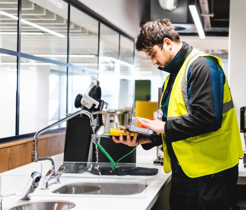 A man in a high vis jacket testing water with a gauge A man in a high vis jacket testing water with a gauge