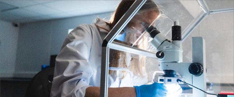 A woman looking into a telescope in a laboratory A woman looking into a telescope in a laboratory
