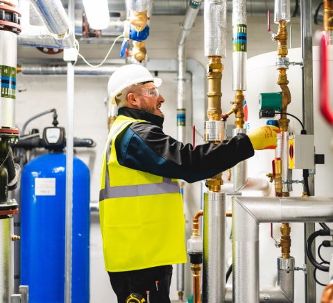 A man with a hard hat and high vis vest looking at a pipe A man with a hard hat and high vis vest looking at a pipe