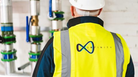 The back of a man in a yellow high vis yellow vest with the Infinity logo The back of a man in a yellow high vis yellow vest with the Infinity logo